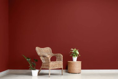 Sepetli ve bordo duvarın yanındaki çiçekli hasır koltuk.