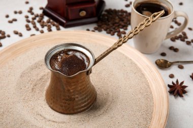 Bir fincan sıcak Türk kahvesi ve kumlu arka planda baharatlar.