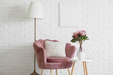 İçinde pembe koltuk, lamba ve vazoda protea çiçekleri olan oturma odası.