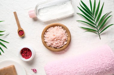 Bir kase doğal vücut fırçası, bir şişe kozmetik ürünü ve hafif arka planda banyo malzemesi.