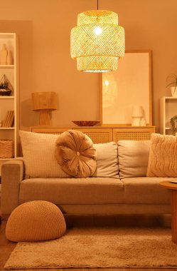 Oturma odasının içinde rahat bir kanepe, puf ve parlayan bir lamba.