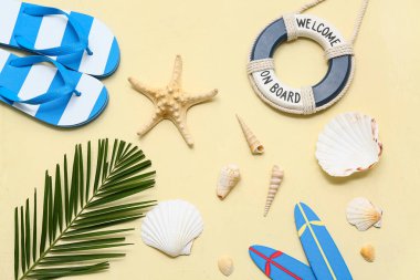 Deniz kabukları ve sarı arka planda palmiye yaprağı olan plaj aksesuarları.