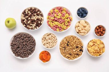 Bowls with different tasty cereals, dry fruits and nuts on white background