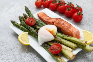 Lezzetli somonlu kızarmış yeşil kuşkonmaz, vişneli domates ve kaynamış yumurta, yakın plan.