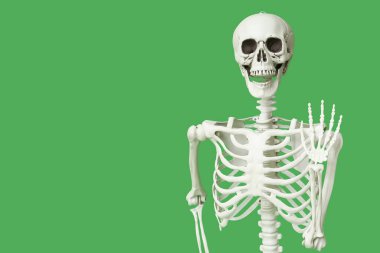 Yeşil arka planda el sallayan insan iskeleti