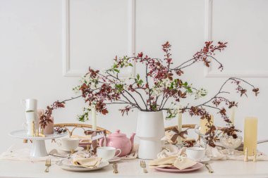 Odada çiçek açan dallar, mumlar ve satranç taşları olan masa ayarı