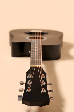 Bej arka planda siyah akustik gitar, yakın plan.