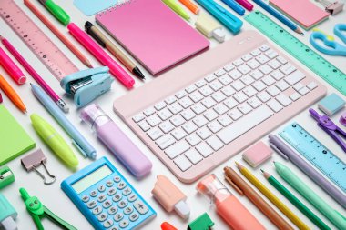 Farklı okul gereçleri ve beyaz arkaplanda bilgisayar klavyesi olan kompozisyon, yakın plan