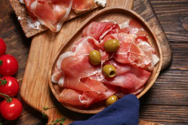 Nefis prosciutto dilimleri, zeytin ve ahşap zemin üzerinde kiraz domatesli tabak.