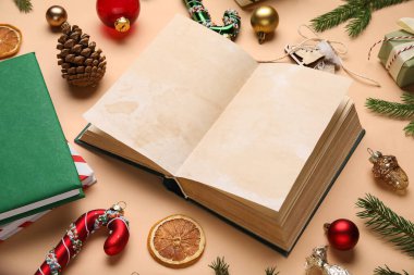 Noel süslemeleri ve bej arka planda köknar dalları olan boş bir kitap. Yakın plan.