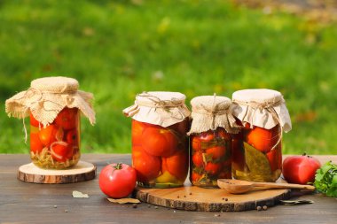 Kavanozlar dolusu konserve domates, kaşık ve ahşap masa malzemeleri.