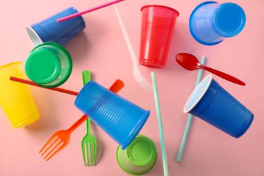 Pembe arka planda uçan renkli plastik sofra takımı