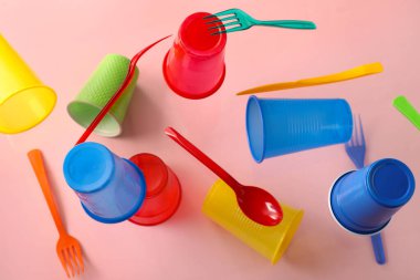 Pembe arka planda uçan renkli plastik sofra takımı