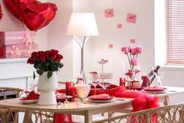 Güllerle dolu şenlik masası, yemek odasında yanan mumlar ve şarap. Sevgililer Günü kutlaması