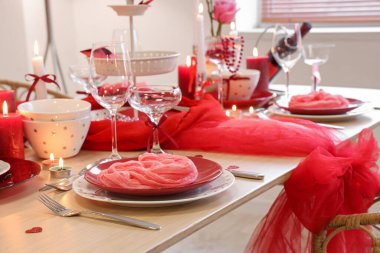 Yemek odasında katlanmış peçete, yanan mumlar ve bardaklarla kutlama masası, yakın çekim. Sevgililer Günü kutlaması