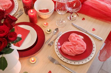 Yemek odasında katlanmış peçete, yanan mumlar ve bardaklarla kutlama masası, yakın çekim. Sevgililer Günü kutlaması