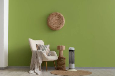 Oturma odasında elektrikli ısıtıcı, koltuk ve masa var.