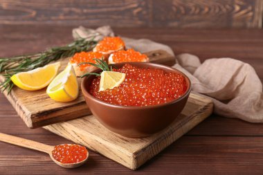 Tahta kesme tahtaları. Lezzetli kırmızı havyar, sandviç, limon ve biberiye.