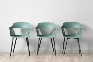 Beyaz duvarın yanındaki modern sandalyeler.