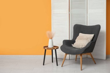 Sarı duvarın yakınındaki, katlanan ekranlı, koltuklu ve masalı odanın içi.