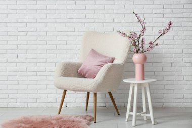 Beyaz koltuklu ve sehpanın üzerinde çiçek açan ağaç dalları olan şık bir oturma odası.