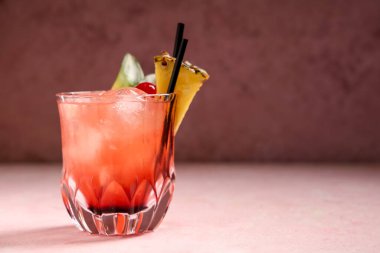 Bir bardak lezzetli Mai Tai kokteyli. Pembe arka planda kiraz ve ananasla süslenmiş.