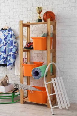 Raflarda farklı malzemeler ve beyaz tuğla duvarın yanında kızaklar var.