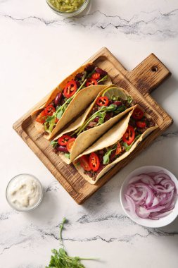 Tahta tepsi, beyaz mermer arka planda taze lezzetli tacolar.