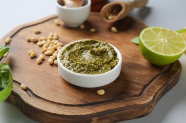 Lezzetli pesto soslu ahşap tahta, beyaz arka planda çam fıstığı ve limon.