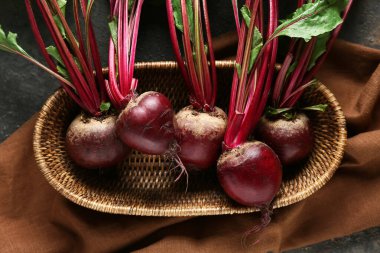 Gri grunge arka planında taze pancar kökleri olan hasır sepet.