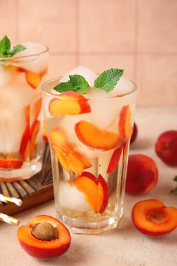 Bir bardak lezzetli soğuk kokteyl ve pembe grunge masasında kayısılar, yakın plan.