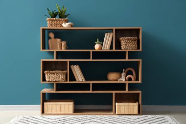 Odada mavi duvarın yanında sepetler olan bir kitaplık.