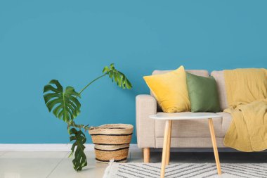 Monstera bitkisi, kanepesi ve masası olan bir oturma odası.