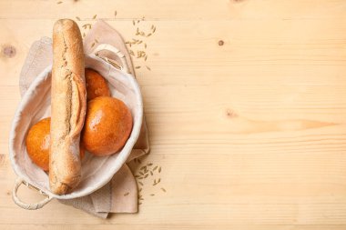 Bir somun taze ekmek ve ahşap masada çörekler.