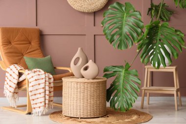 Monstera bitkisi, koltuk ve sepeti olan bir oturma odası.