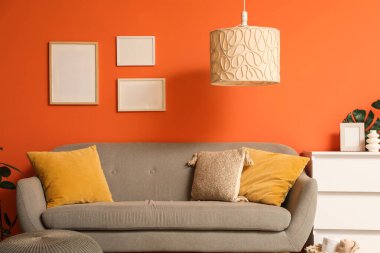 Çekmece, puf ve kanepe turuncu duvarın yanında, oturma odasının içinde, yakın plan.