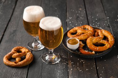 Siyah ahşap arka planda soğuk bira ve simit bardaklarıyla kompozisyon, yakın plan.