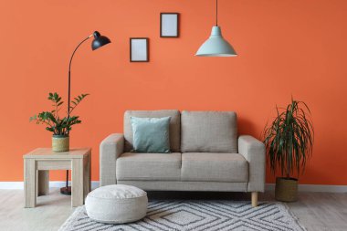 Şık oturma odasının içinde rahat gri kanepe, puf ve standart lamba.