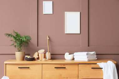 Odanın içinde farklı masaj fırçaları, deniz tuzu, katlanmış havlular ve kahverengi duvarın yanında klozet var.