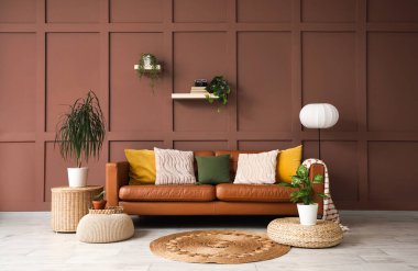 Şık, kahverengi kanepeli, puflu ve çiçekli bir oturma odası.