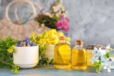 Mavi ahşap masanın üzerinde kurumuş çiçeklerle birlikte gerekli yağ şişeleri.