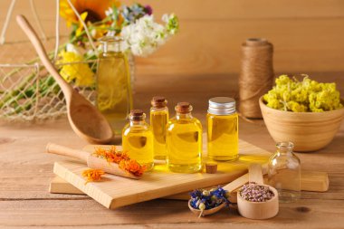 Ahşap zemin üzerinde kurumuş çiçekler olan gerekli yağ şişeleri.