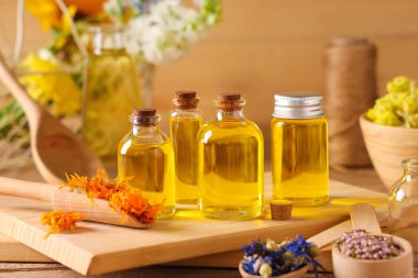 Ahşap zemin üzerinde kurumuş çiçekler olan gerekli yağ şişeleri.