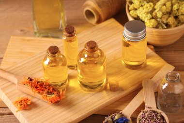 Ahşap zemin üzerinde kurumuş çiçekler olan gerekli yağ şişeleri.