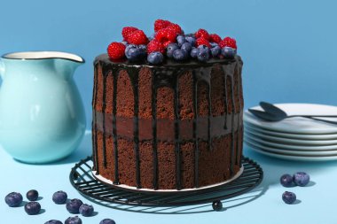 Taze böğürtlenli çikolatalı pasta ve mavi arka planda bir sürahi süt.