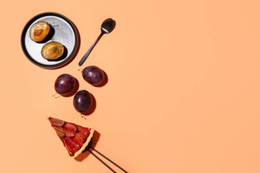 Lezzetli erikli turta, taze meyve, turuncu arka planda spatula ve kaşık.