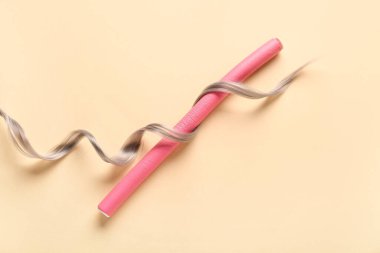 Bej arka planda köpük bigudiyle gri saç teli.