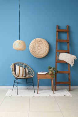 Konforlu koltuk, sehpa sehpası ve mavi duvarın yanındaki merdiven.