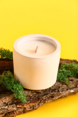 Sarı zemin üzerinde mum ve ağaç kabuğu olan tutucu