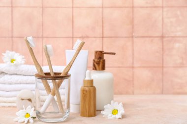 Masadaki banyo malzemeleri ve çiçekler renkli fayanslara karşı.